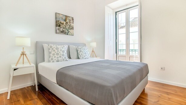 A bedroom with a bed, two bedside tables, a window, and a door. - Olarias Terrace Lisbon III (Lisbon)