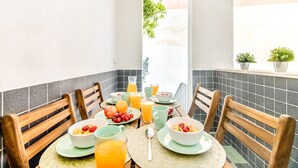 A breakfast table with chairs, plates, bowls, and glasses of orange juice. - Olarias Terrace Lisbon III (Lisbon)