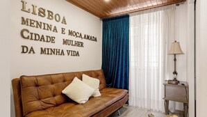A room with a brown leather sofa, a small table with a lamp, and a wall with a text in Portuguese. - Alfama The Best II, in Old Lisbon (Lisbon)