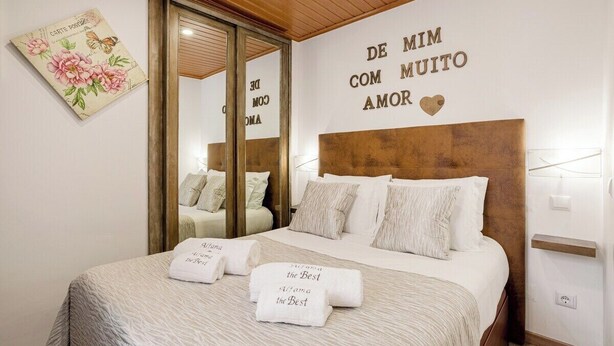A hotel room with a bed, a mirror, a wall with a message, and a floral artwork. - Alfama The Best II, in Old Lisbon (Lisbon)