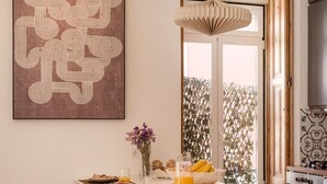 Une cuisine moderne dotée d’un îlot central, de tabourets de bar, d’un luminaire suspendu et d’un grand tableau abstrait accroché au mur.