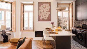 Une cuisine moderne dotée d’un îlot central, de grandes fenêtres et d’un coin repas avec un canapé.
