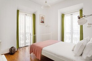 Ein Schlafzimmer mit einem Bett, einer Nachttischlampe, einem Bild an der Wand und einem Fenster mit Vorhängen.