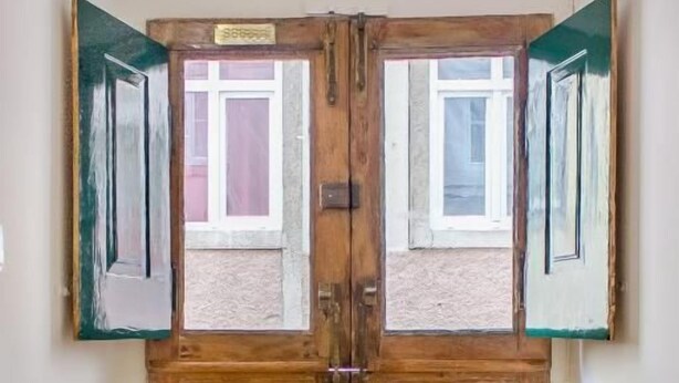 Una porta doble de fusta amb un felp de porta negre al davant.
