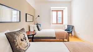 Ein Schlafzimmer mit Bett, Nachttisch, Lampe, Sessel und einem Fenster mit Blick.