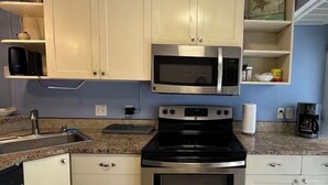 A kitchen with white cabinets, a stainless steel microwave, a stove, and a dishwasher. - Quaint 1-bedroom island condo in Corpus Christi with all the comforts of home. (Corpus Christi)
