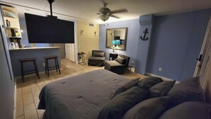 A bedroom with a bed, a desk, a chair, and a small table with a lamp. - Quaint 1-bedroom island condo in Corpus Christi with all the comforts of home. (Corpus Christi)