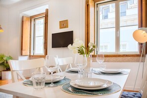 A dining table set with plates, glasses, and a vase of flowers. - Chiado Central Apartment, the Heart of Lisbon (Lisbon)