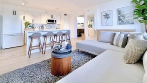 Una sala de estar moderna con un sofá, una mesa de centro y una zona de cocina al fondo.