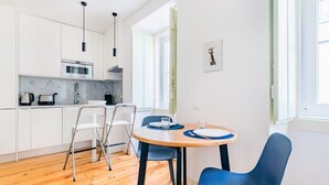 Une cuisine moderne avec des meubles blancs, une table à manger en bois et des chaises bleues.
