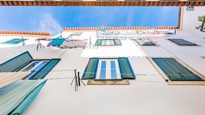 Une terrasse sur le toit, dotée de nombreuses fenêtres, dont certaines sont équipées de volets, et où du linge est étendu sur des cordes à linge.