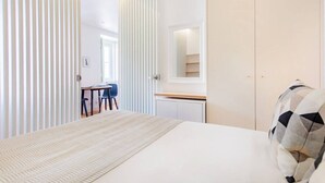 Une chambre à coucher comprenant un lit, un bureau, une chaise, une armoire et un miroir.