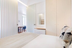 Ein Schlafzimmer mit Bett, Schreibtisch, Stuhl, Kleiderschrank und Spiegel.