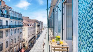 En balkon med et bord, stole og en blomstervase.