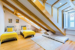 Ein Schlafzimmer mit zwei Betten, einem weißen Teppich, Holzbalken und einem großen Fenster.