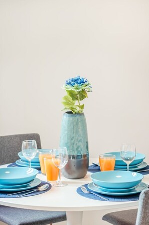 Ein Esstisch mit blauen Tellern, Gläsern und einer Vase mit Blumen.