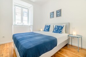 Ein Schlafzimmer mit Bett, Fenster, Nachttisch und Wandbildern.