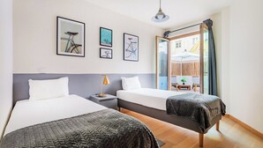 Ein Hotelzimmer mit zwei Betten, einem Nachttisch, einer Lampe und gerahmten Bildern an der Wand.