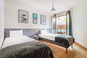Ein Hotelzimmer mit zwei Betten, einem Nachttisch, einer Lampe und gerahmten Bildern an der Wand.