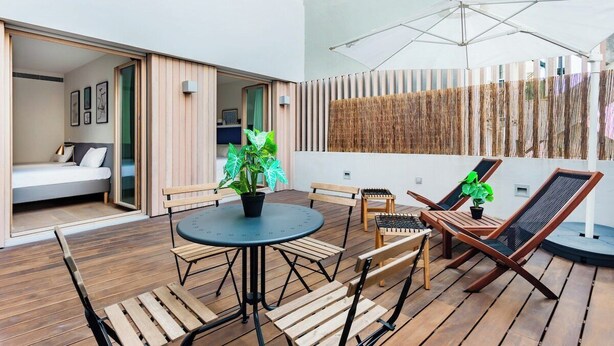 Eine moderne Terrassengruppe im Freien mit rundem Tisch, Holzstühlen und Liegestühlen.
