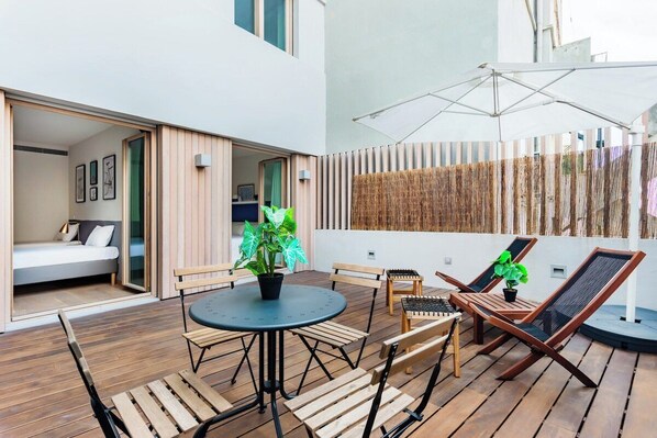 Eine moderne Terrassengruppe im Freien mit rundem Tisch, Holzstühlen und Liegestühlen.