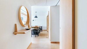 Ein modernes Interieur mit Holzboden, einem runden Spiegel, einer Essecke mit Stühlen und Tisch sowie einer hängenden Pendelleuchte.