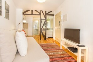 Ein modernes Wohnzimmer mit Sofa, Fernseher und Holzbalken.