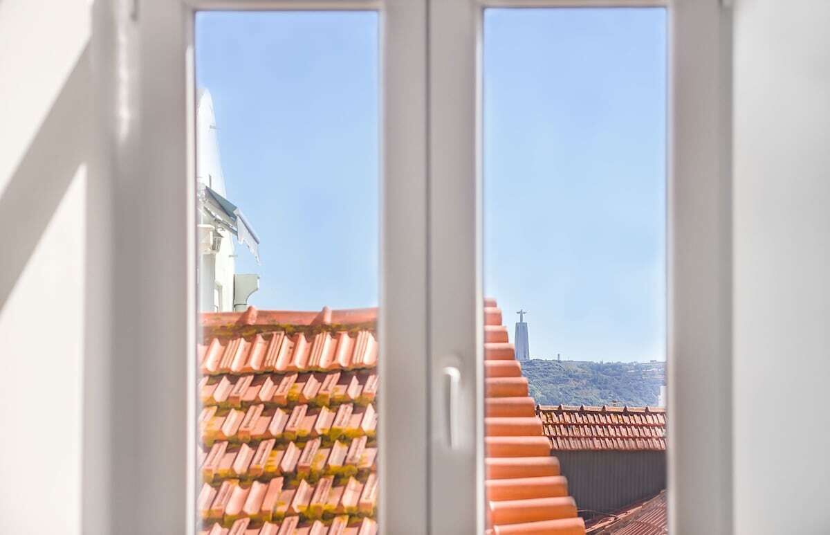 A view through a window with a tiled roof and a building in the background.