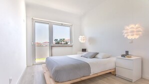 A bedroom with a bed, bedside tables, a nightstand, a window, and a view of the outside. - Graça Amazing River Views (Lisbon)