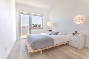 A bedroom with a bed, bedside tables, a nightstand, a window, and a view of the outside. - Graça Amazing River Views (Lisbon)