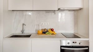 Une cuisine équipée d’un évier, d’un plan de travail avec des fruits et un verre de jus d’orange, ainsi que d’un four.