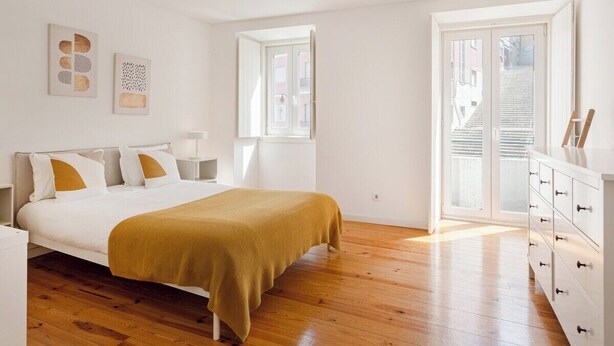 Une chambre à coucher avec un lit, une commode, une fenêtre et une porte.