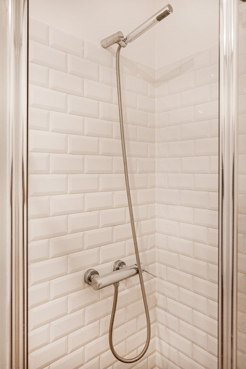 Une douche équipée d’un pommeau de douche à main et d’un robinet mural fixe.