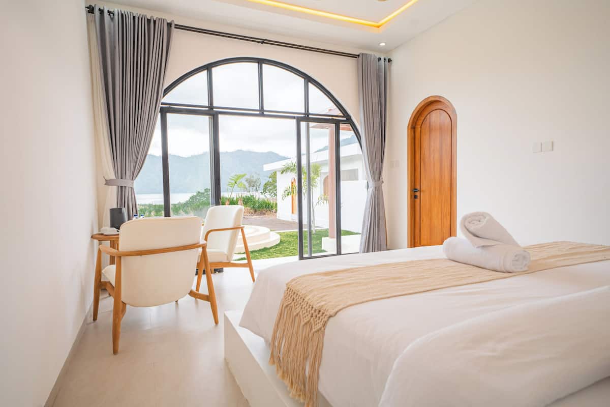 Habitación de hotel con una cama grande, un escritorio, una silla y vistas al exterior.