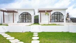 A modern building with two white structures, each featuring large arched windows and a covered patio area. - Lazura Serenite (Kintamani)