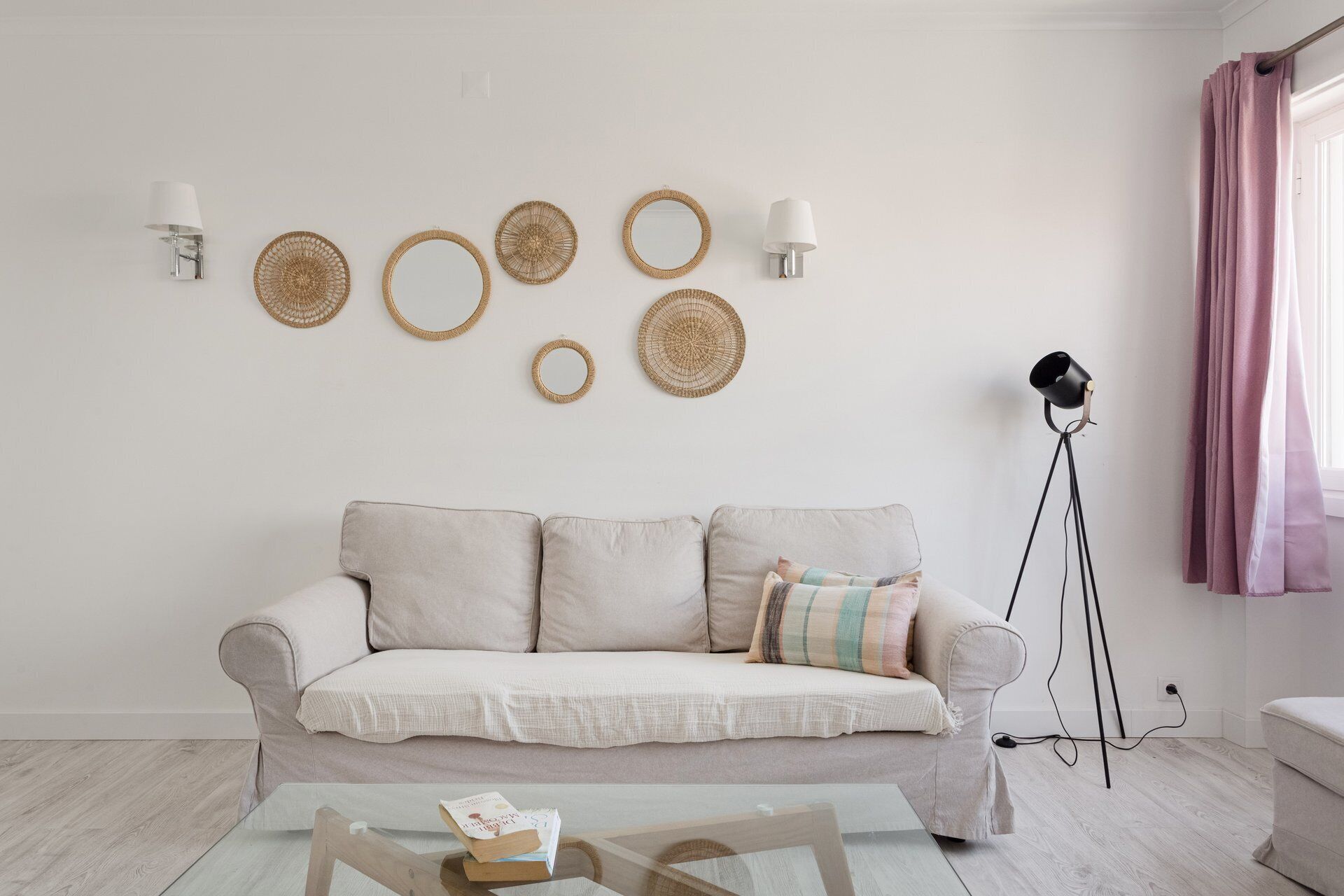 A living room with a sofa, wall-mounted lamps, and a floor lamp.