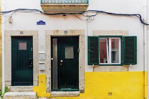 Ein Gebäude mit zwei Eingängen, wobei einer mit 'Casa d'Santana' und der andere mit 'Casa d'Angelo' beschriftet ist, und ein Fenster mit grünen Fensterläden.