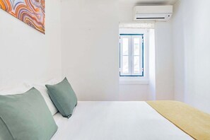 Ein Zimmer mit einem Bett, Kissen, einer Klimaanlage und einem Fenster.