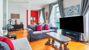A living room with a grey sofa, red cushions, a patterned coffee table, and a flat-screen TV. - Douradores Downtown Flat (Lisbon)