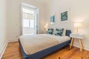 Ein Schlafzimmer mit einem Bett, einem Nachttisch, einer Lampe und zwei an der Wand befestigten Bildern.
