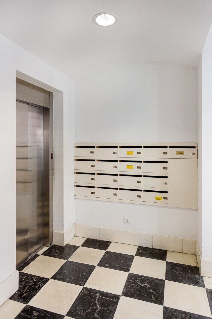 An elevator, a row of mailboxes, and a checkered floor.