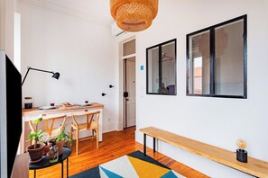 Ein modernes Zimmer mit einem Holztisch, Stühlen, einer Bank, einer Hängelampe und zwei gerahmten Bildern an der Wand.