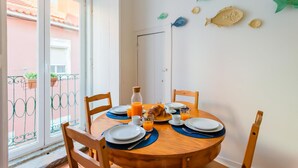 Una mesa con platos, cubiertos y un croissant, con vistas a un balcón y una puerta al fondo.