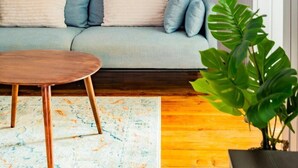 Un salón moderno con un sofá azul claro, una mesa de centro de madera y un cuadro abstracto azul grande en la pared.