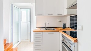 Una cocina moderna con armarios blancos, una encimera de madera, un fregadero y un horno.