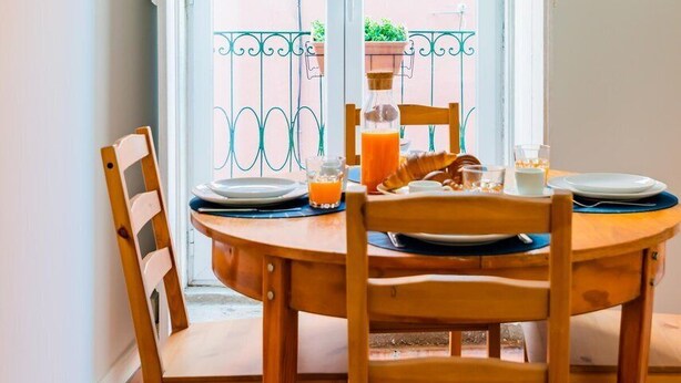 Una mesa de comedor con sillas, un vaso de jugo de naranja y una botella de agua.