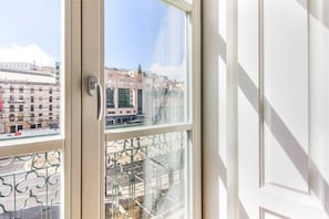 Ein Fenster mit Blick auf Gebäude, einem Metallgeländer und einem Türrahmen.