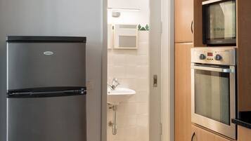 A kitchen with a stainless steel refrigerator, wooden cabinets, and a built-in oven.