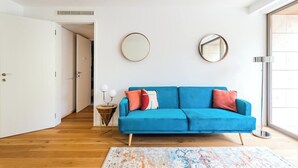 Un salon moderne avec un canapé bleu, un tapis à motifs et deux miroirs fixés au mur.