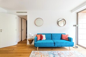 Ein modernes Wohnzimmer mit einem blauen Sofa, einem gemusterten Teppich und zwei Wandspiegeln.